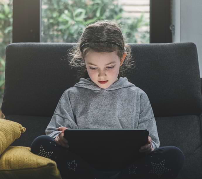 fată pe canapea folosind un laptop care lansează Norton Family.