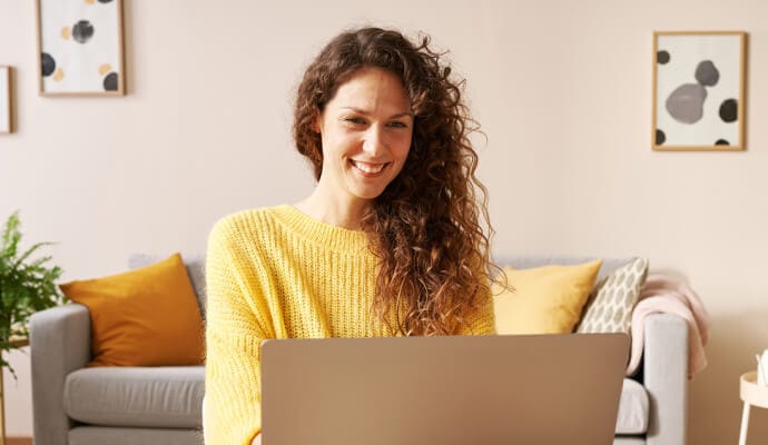 Doamnă zâmbind folosind un laptop care lansează Norton Safe Search.